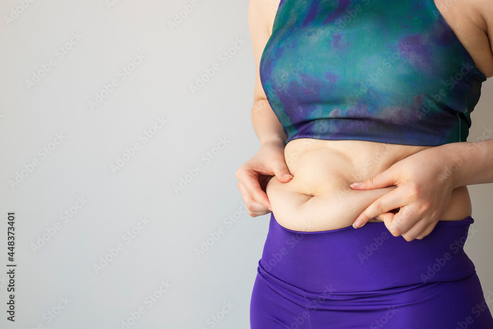 Woman hand holding her own belly fat and cellulite on white background. Women before weight loss and shape up healthy stomach muscle concept. - obrazy, fototapety, plakaty 
