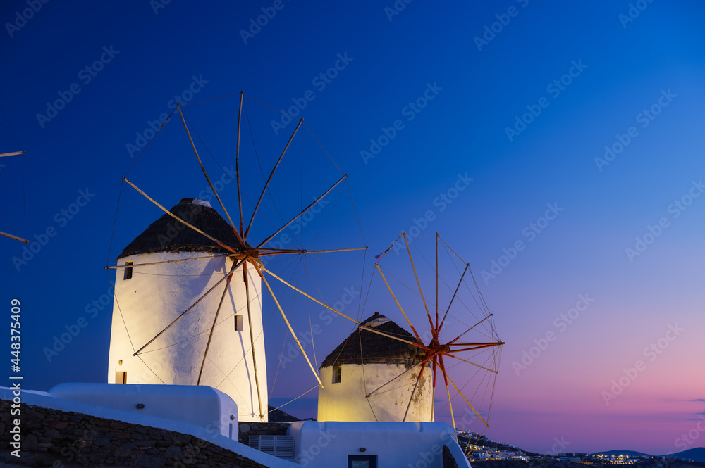 Mykonos, Greece. Traditional windmills. The symbol of Mykonos during  sunset. Landscape during sunset. Sea shore and beach. Photo for travel and vacation.