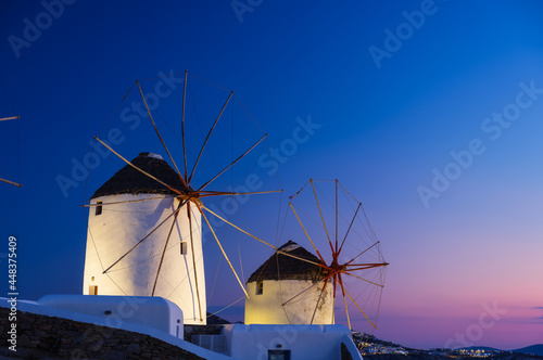Mykonos, Greece. Traditional windmills. The symbol of Mykonos during sunset. Landscape during sunset. Sea shore and beach. Photo for travel and vacation.