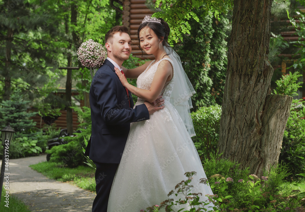 Portrait of an international loving couple of newlyweds against the backdrop of nature and flowers