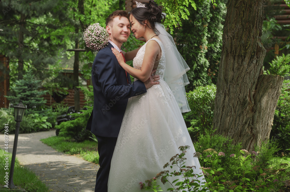 Portrait of an international loving couple of newlyweds against the backdrop of nature and flowers