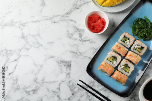 Delicious sushi rolls served on white marble table, flat lay. Space for text