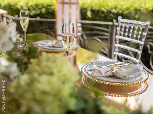 Foto Glasses of champagne and a sumptuously served table in a summer restaurant waiting for dear guests