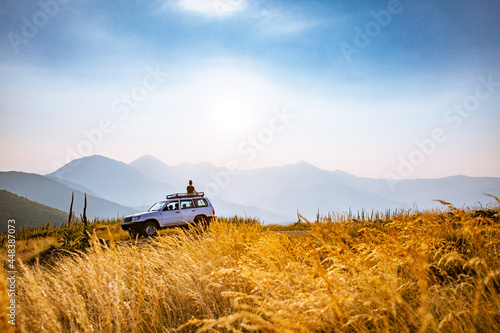 Person enjoying sunset on top of 4x4 vehicle in the mountains of the Nationalpark Sharr, Brezovicë, Kosovo