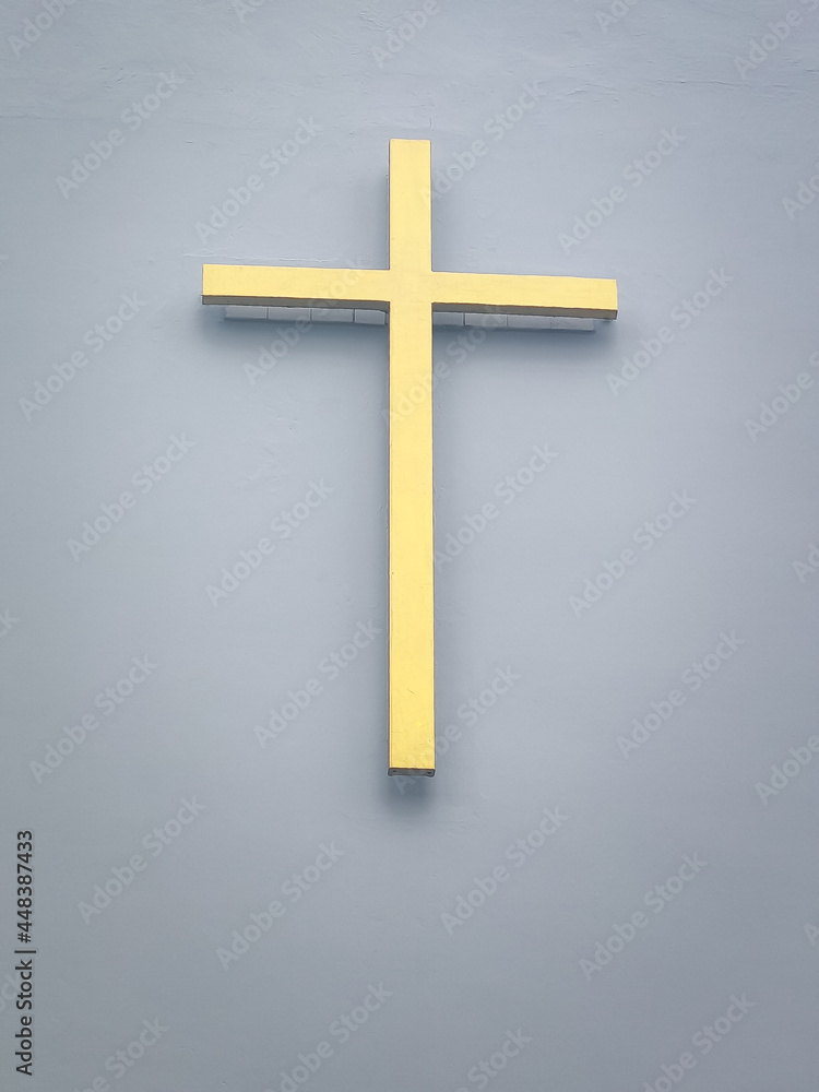 Golden crucifix mounted on the church wall. Symbol of Christianity.