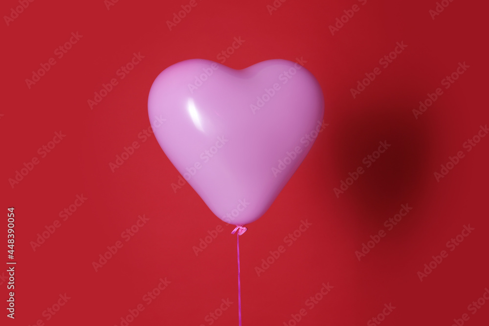 Festive heart shaped balloon on red background