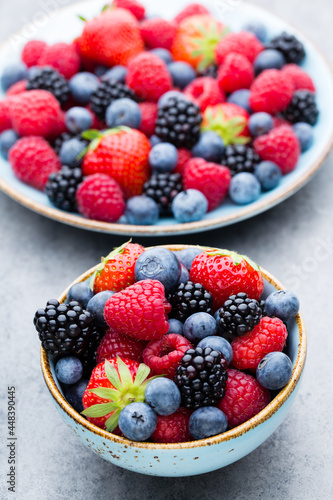 Fresh berry salad on blue dishes. Vintage wooden background.