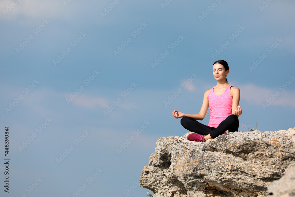 Young woman meditating on cliff. Space for text Young woman meditating on cliff. Space for text
