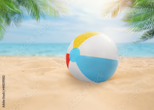 Colorful beach ball on sandy coast near sea