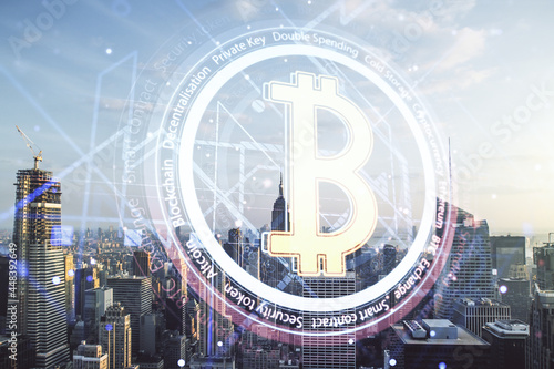 Double exposure of creative Bitcoin symbol hologram on Manhattan office buildings background. Mining and blockchain concept