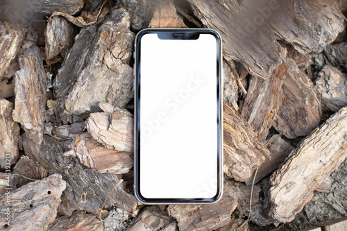 Mockup image blank white screen modern cell phone outdoors on the background of pine bark. background empty space for advertise text