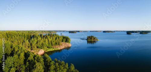 Aerial Panorama of Scandinavian green pine tree forest, dark blue sea with few small islands, Baltic Sea on horizon. Sunny day, Northern Scandinavia. Drone photo.