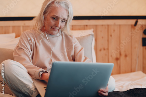 Senior Adult Woman with laptop and mibile headphones relaxing at glamping camping tent. Modern vacation lifestyle concept