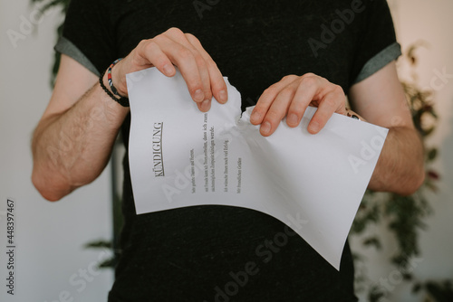 Young Man in black T-Shirt tearing  down resignation letter