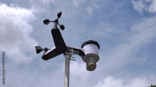time lapse solar weather station for meteorological research with indicator and wind speed, rain gauge, temperature control, bottom view with passing clouds in the background
