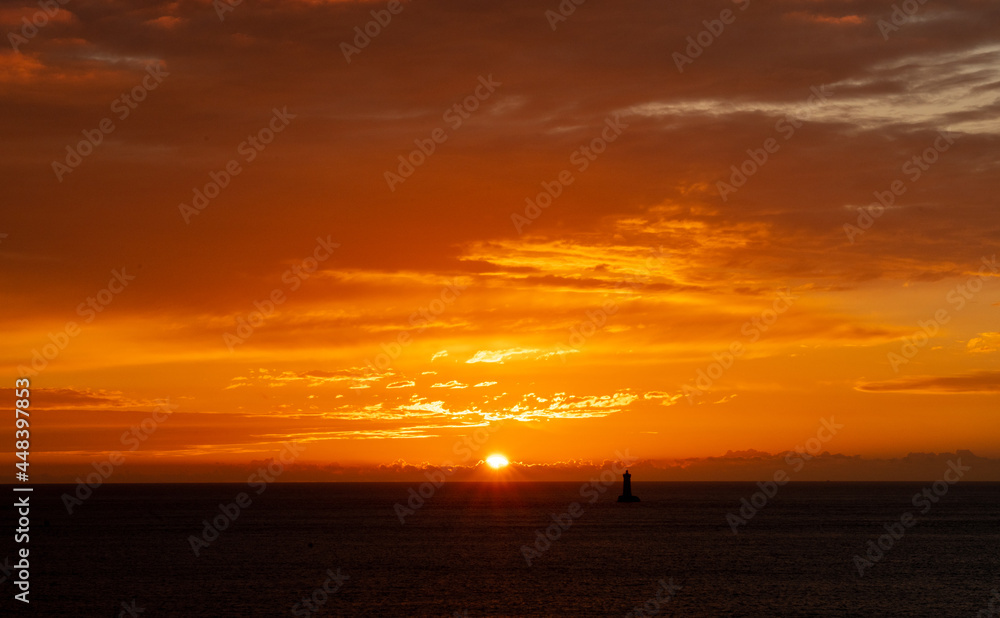 einzigartiger Sonnenuntergang über dem atlantischen Ozean vor der Küste von Porspoder mit dem Leuchtturm der vier (Phare du Four), Bretagne, Frankreich