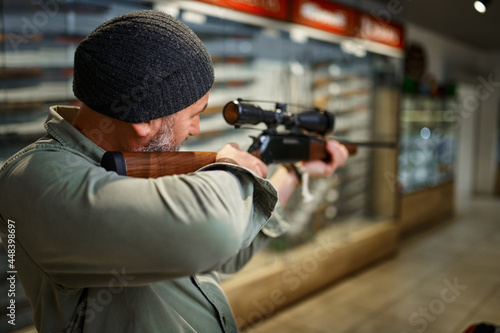 Hunter buying rifle with optical sight, gun store