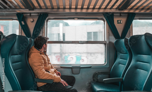 Young boy alone in the wagon, looking out the window of an old train. Explorer trip around the world.