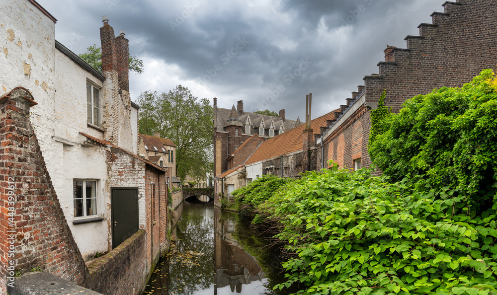 Blick auf historische Häuser an einem Kanal in der Altstadt vonBrügge mit spektakulärem Himmel, Belgien