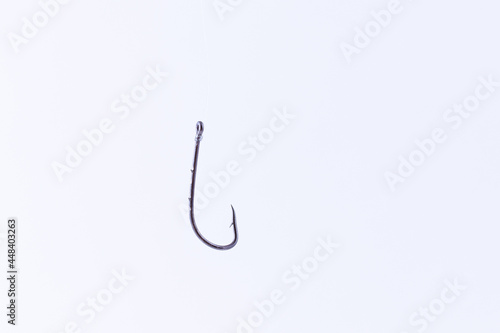 Black Fishing Hook Hanging on a Fishing Line Against a White Background