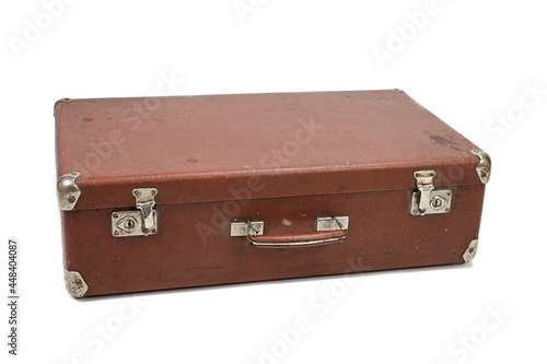 Old cardboard brown suitcase with metal corners and clasps. The suitcase lies horizontally with the handle towards the camera