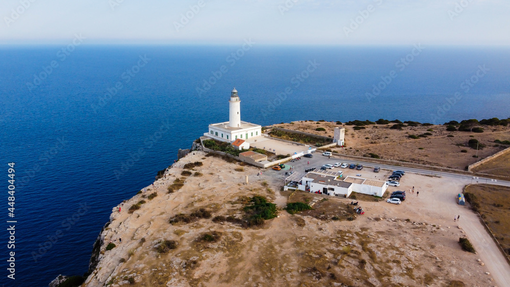 Aerial view of the Far de la Mola, a lighthouse at the southeastern tip of Formentera island in the Balearic, Islands, Spain - White lighthouse at the top of a cliff in the Mediterranean Sea
