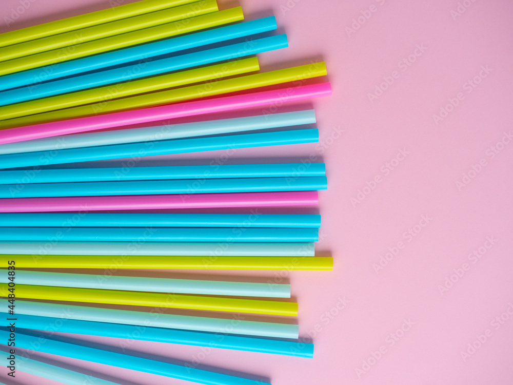 Close-up of multicolored plastic tubes on a pink paper background. Top view, flat lay Close-up of multicolored plastic tubes on a pink paper background. Top view, flat lay