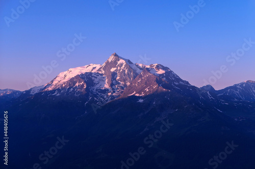 Pink sunrise or sunset on mountain. Beautiful landscape with clear sky over the summit of a valley in alps.