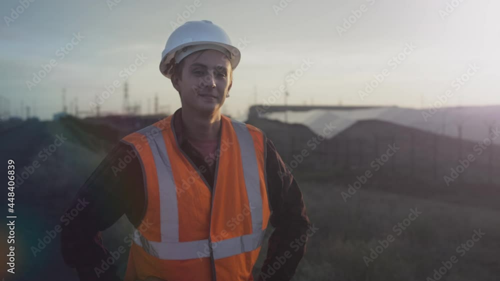 Portrait of a young engineer next to solar panels during sunset. Checks the health and efficiency of renewable energy sources and solar cells. Solar panel plantation. Concept of green energy. Portrait of a young engineer next to solar panels during sunset. Checks the health and efficiency of renewable energy sources and solar cells. Solar panel plantation. Concept of green energy.