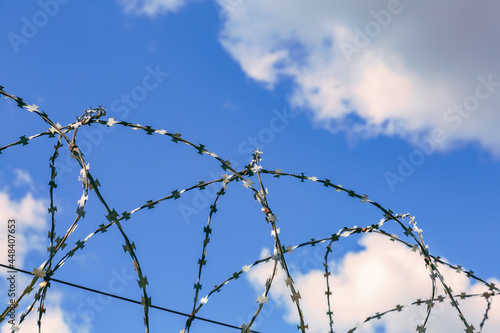 Barbed wire and blue sky as symbols of injustice and freedom