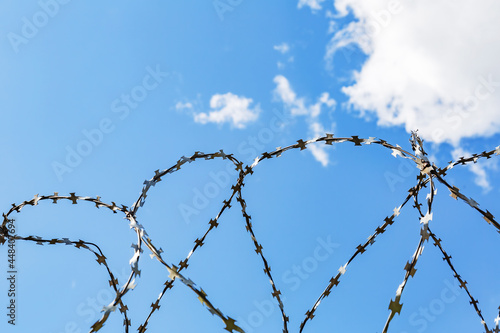 Barbed wire and blue sky as symbols of injustice and freedom