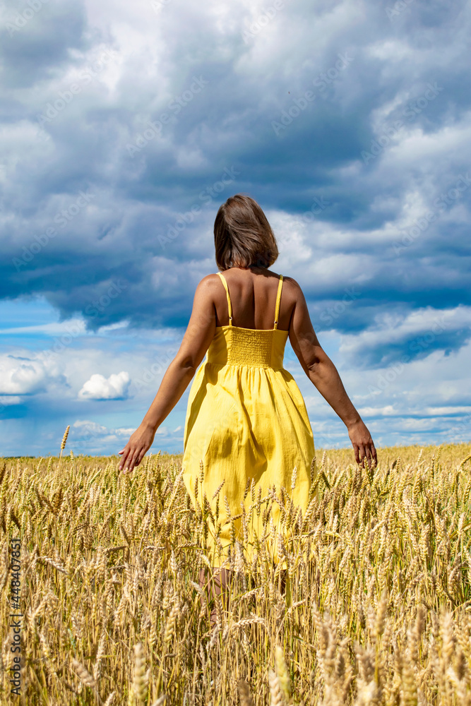 Naklejka premium A young girl dances and enjoys life in the wheat field. Lifestyle concept.