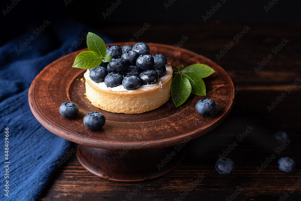 Plate with blueberry tart on a dark wooden background, berry pie. Plate with blueberry tart on a dark wooden background, berry pie.