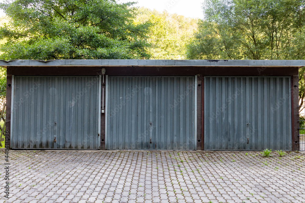 a three car garage standing alone on a roadside. a rustic old garage with steel doors. Symmetry in the architecture. a three car garage standing alone on a roadside. a rustic old garage with steel doors. Symmetry in the architecture.
