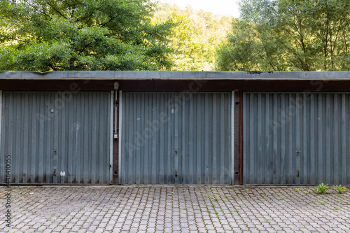 a three car garage standing alone on a roadside. a rustic old garage with steel doors. Symmetry in the architecture. 