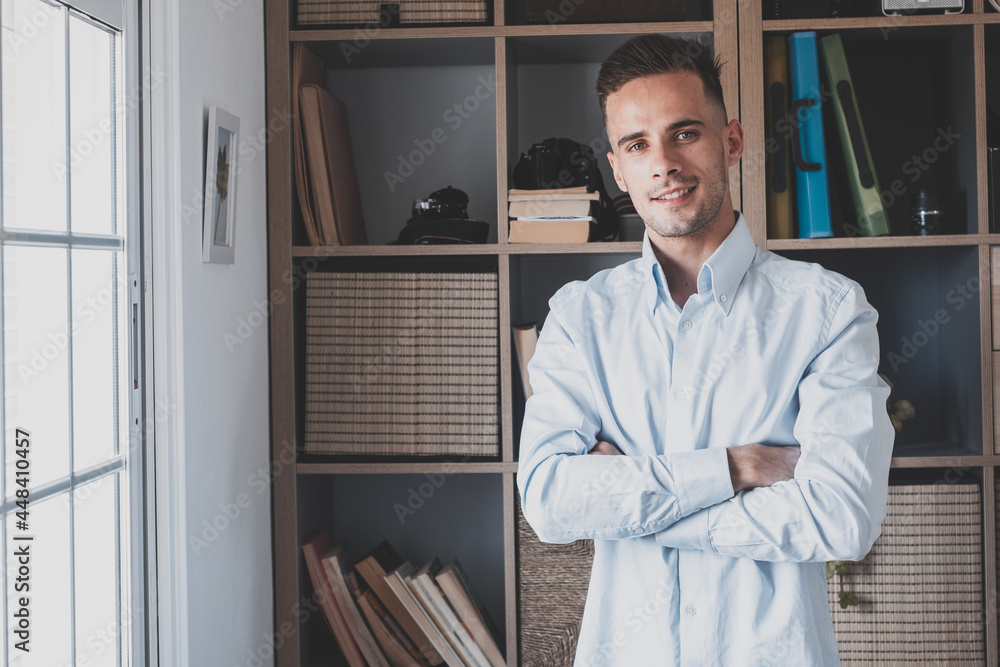 Fototapeta premium Portrait of one young cheerful male smiling having fun at home. Attractive young caucasian man studying independent looking at the camera and posing to picture. 