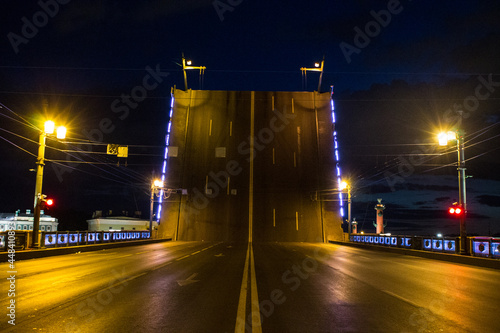 raised road with road markings and palace bridge lights blocked the movement of cars on a summer night with illumination against a dark sky in Saint-Petersburg Russia