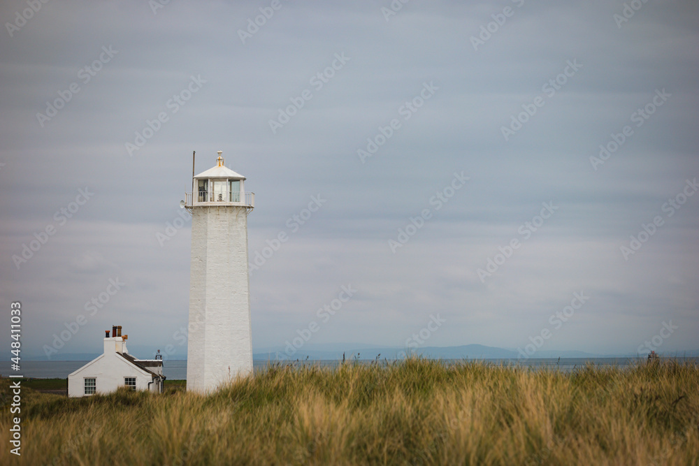 Rugged exposed landscape of dune grassland on Walney Island with the lighthouse and cottage