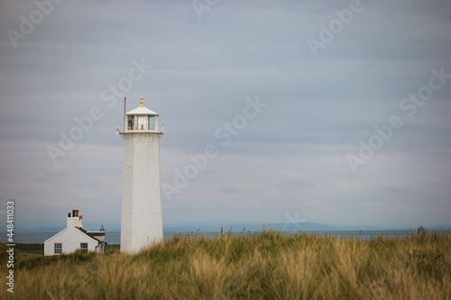Rugged exposed landscape of dune grassland on Walney Island with the lighthouse and cottage