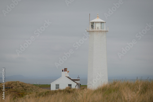 The Walney lighthouse and cottage on Walney Island in grassland by the Irish Sea photo