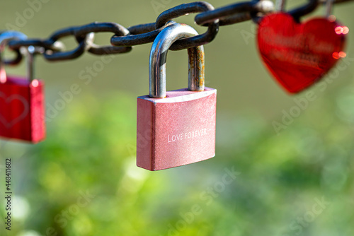 A pink padlock hanging on a chain engraved with the words love forever.