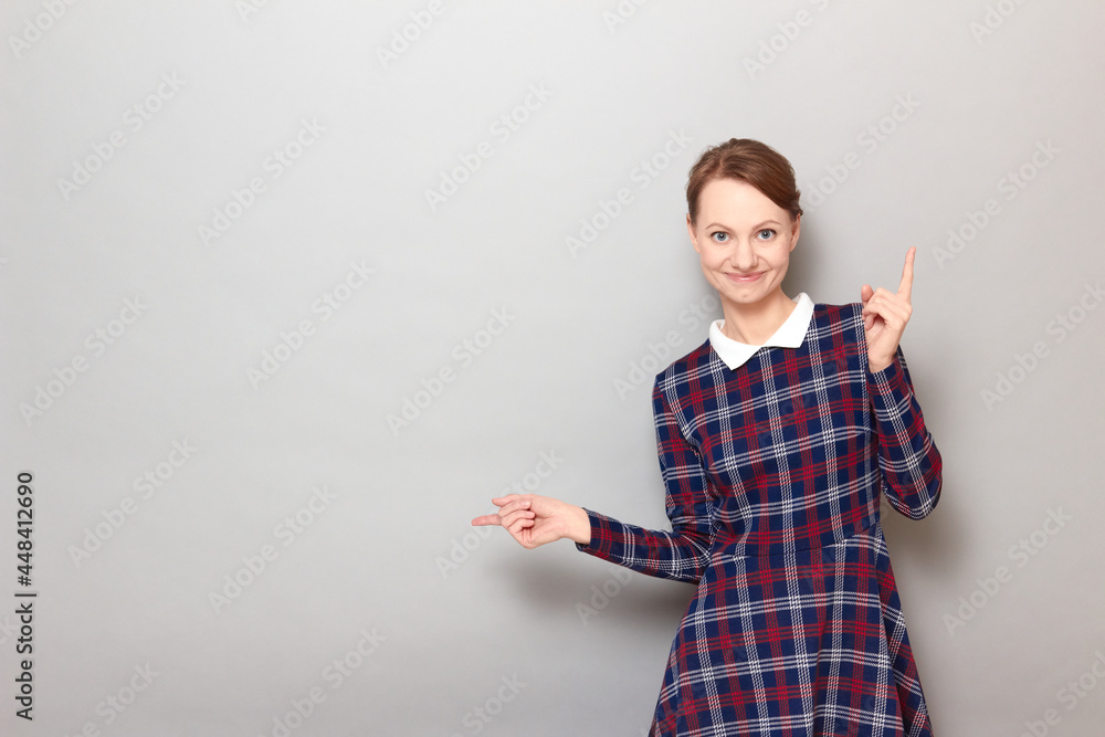 Happy pretty blond girl is pointing with both hands at copy spaces