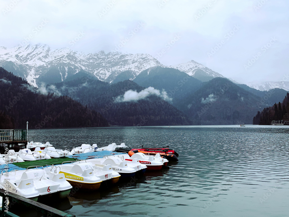 Blue lake, boats, mountains, snowy peaks, fog. Lake Ritsa