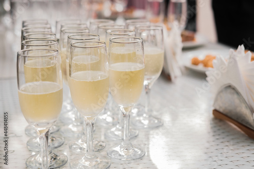 Elegant champagne glasses, standing in a row on the serving table during a party or celebration.