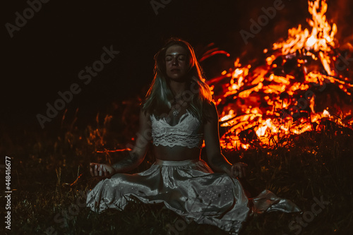 beautiful meditating woman by the fire.