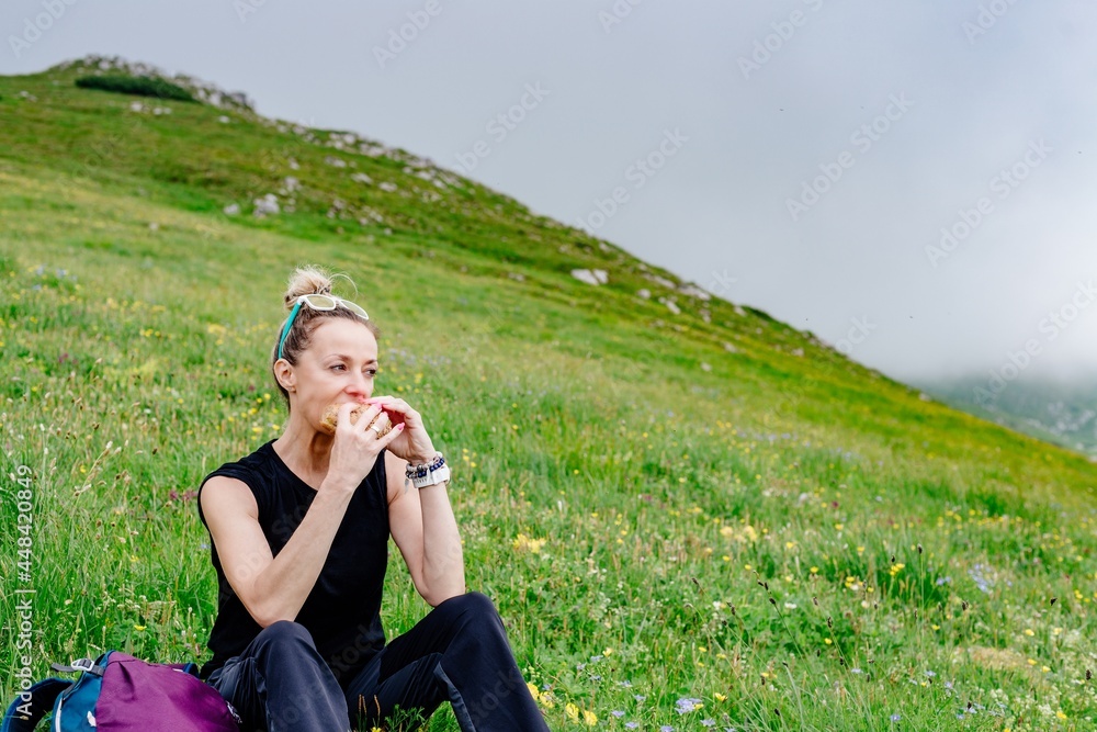 Young woman eating vegetarian sandwich on nature background. A beautiful day in the mountains. Young woman eating vegetarian sandwich on nature background. A beautiful day in the mountains.