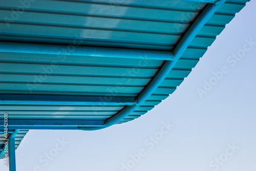 Low angle view of blue metallic waving roof against the blue sky. Minimalism concept. 