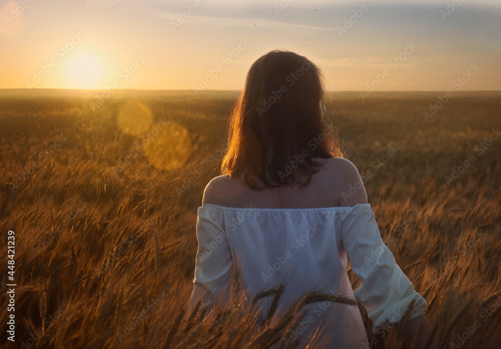 a young woman walks through a wheat field
