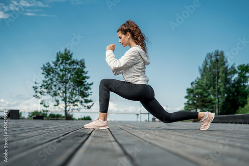 Burns calories in the body. Exercises stretching muscles for fitness are active. The athlete is a runner who leads a healthy lifestyle. Athletic figure a woman trains on the street in the city.