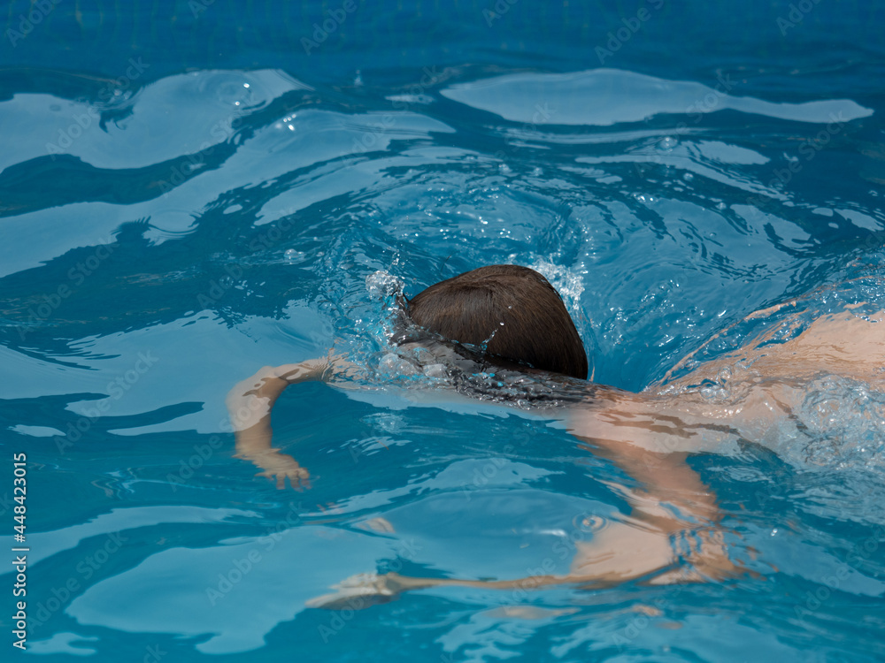 Obraz premium Boy in the swimming pool diving into the water diving